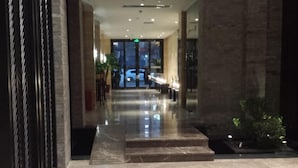 A modern hotel lobby with a marble floor, a reception desk, and a glass door entrance. - Gurun Eco Hotel (Luoyuan)