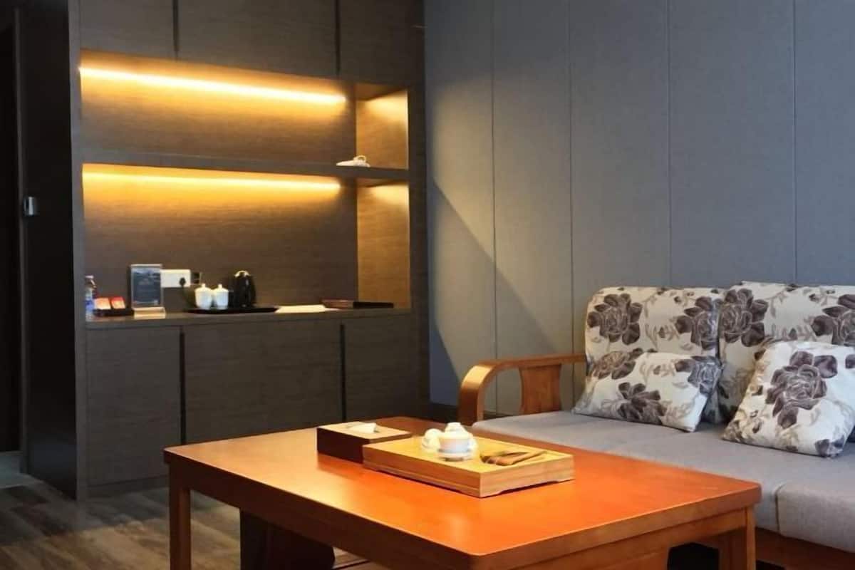 Una sala de estar moderna con sofá, una mesa de madera y una cocina integrada con encimera e iluminación colgante.