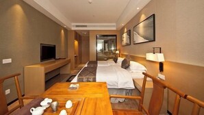 A hotel room with a bed, bedside table, lamp, TV, and a view into the hallway. - Gurun Eco Hotel (Luoyuan)