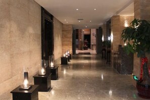 A corridor with a polished marble floor, a reception desk, and a potted plant. - Gurun Eco Hotel (Luoyuan)