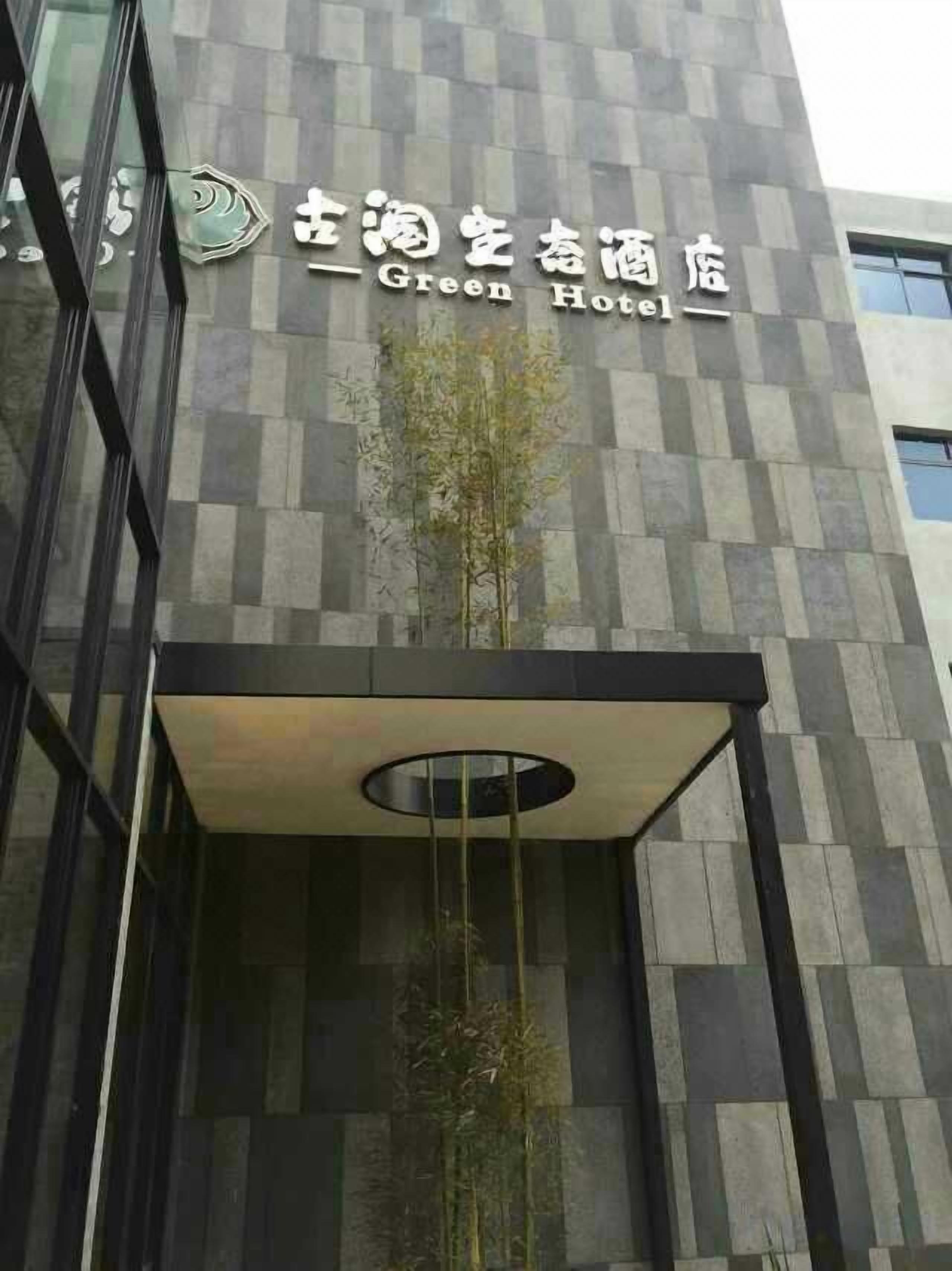 The exterior of the Green Hotel with a modern architectural design, featuring a checkered facade and a prominent entrance with a hanging plant.