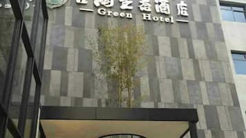 The exterior of the Green Hotel with a modern architectural design, featuring a checkered facade and a prominent entrance with a hanging plant.