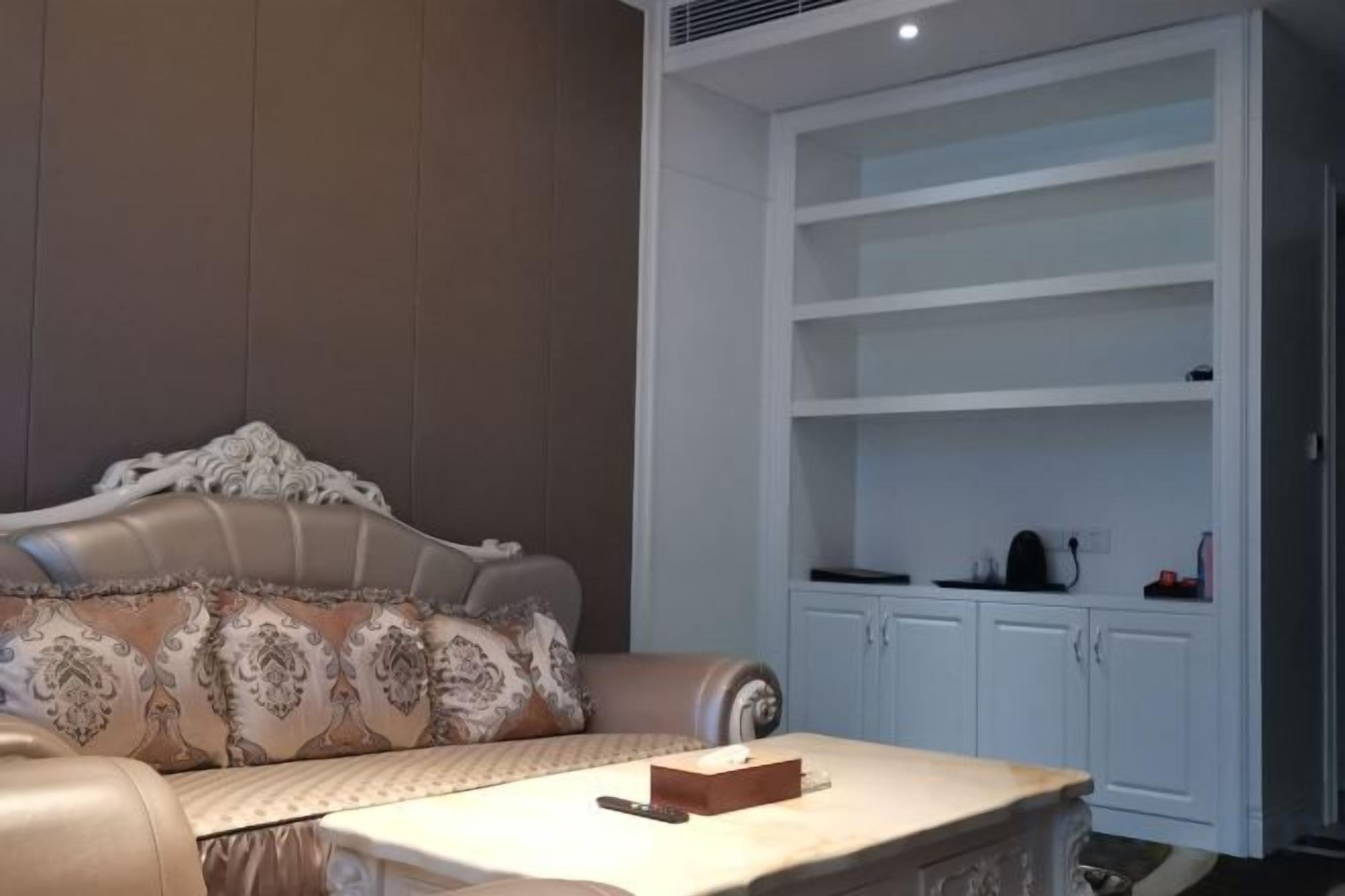A living room with a sofa, a coffee table, and a white shelving unit.