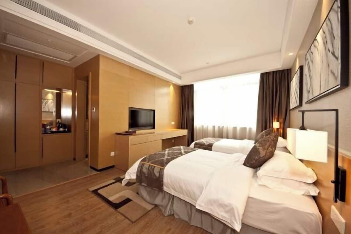 Una habitación de hotel con cama, escritorio, televisor y armario.