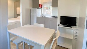 Une cuisine compacte avec un coin repas, un téléviseur et une fenêtre donnant sur l’extérieur.