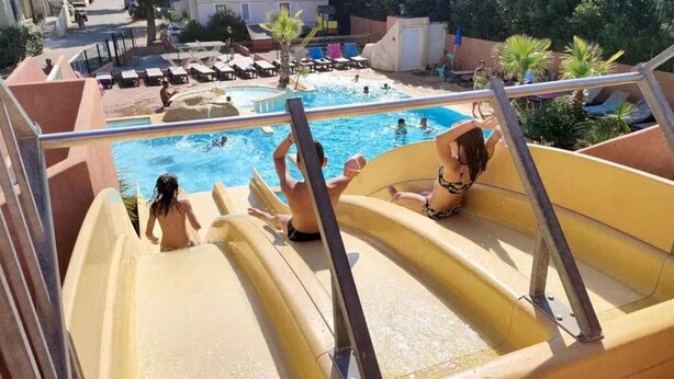 Tobogán de agua en un resort, con un área de piscina al fondo.
