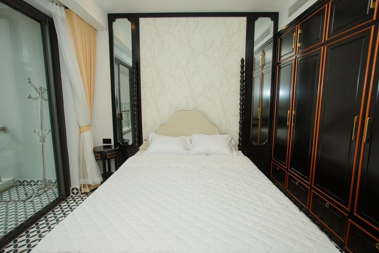 A bedroom with a large bed, a wardrobe, and a glass shower area.