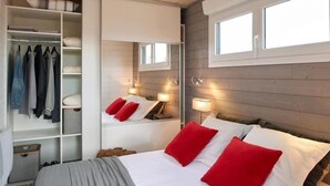 Ein Schlafzimmer mit einem Bett, roten und weißen Kissen, einem Kleiderschrank und einem Spiegel.