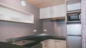 Une cuisine de taille réduite équipée d’un évier, d’une cuisinière, d’un four à micro-ondes et d’un réfrigérateur.