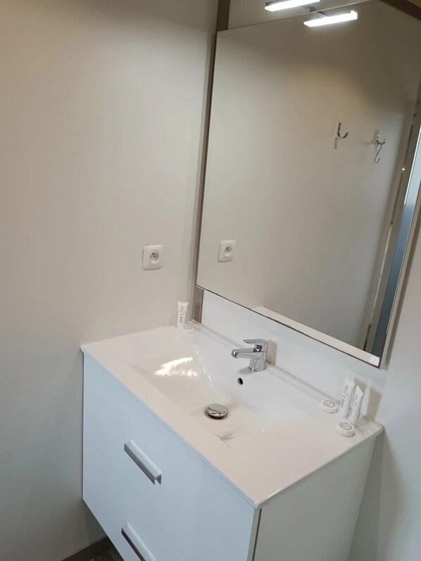 Un baño moderno con tocador blanco, espejo y lavabo.