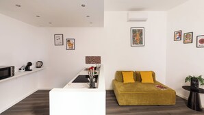 Een moderne woonkamer met een witte bank, een geel kussen en een salontafel met een plant.