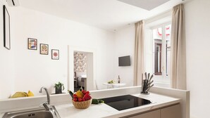Een moderne keuken met een roestvrijstalen spoelbak, een mand met fruit en een flatscreen televisie aan de muur.