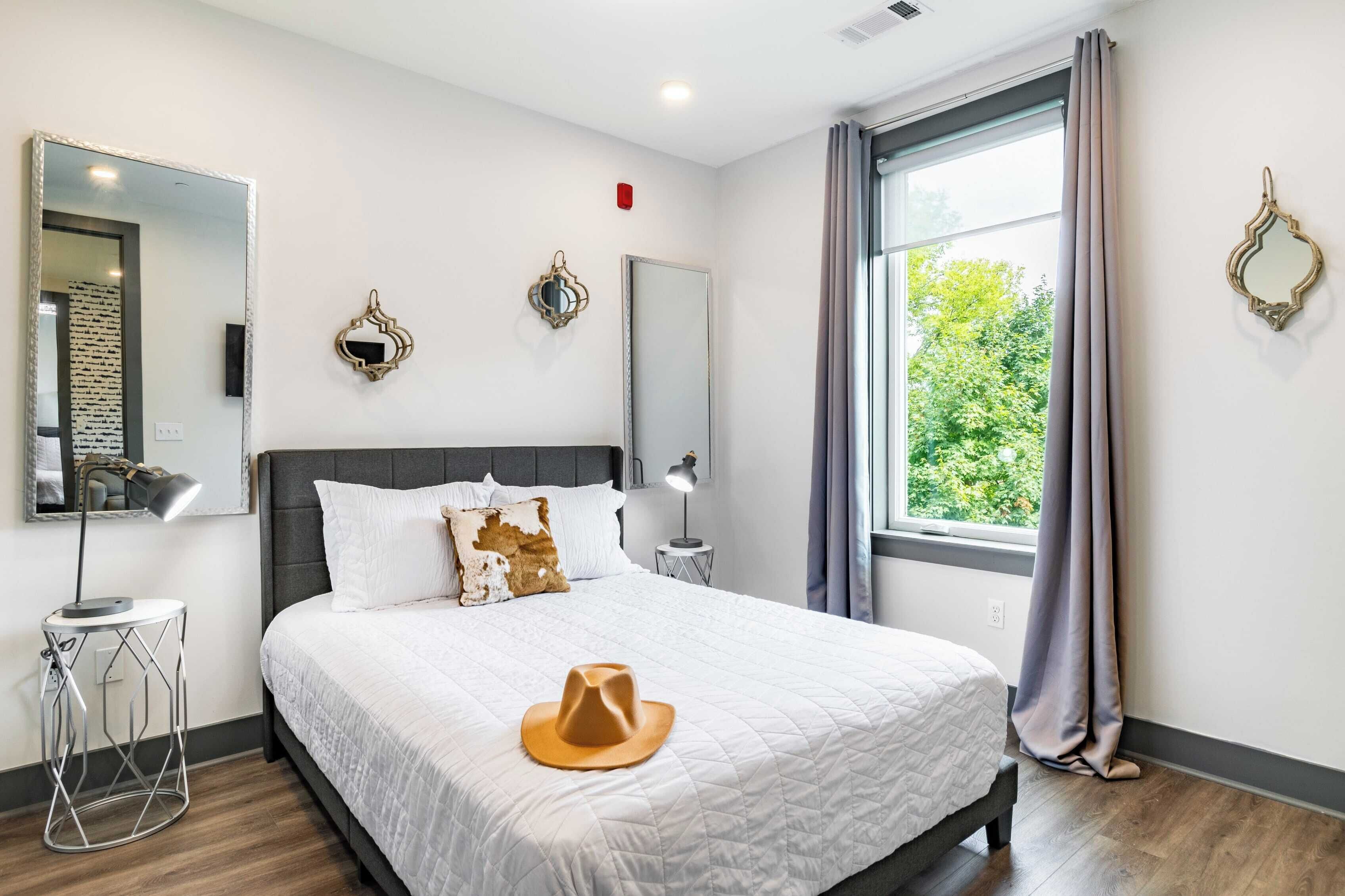 Un dormitorio moderno con una cama grande, lámparas de noche y espejos decorativos.