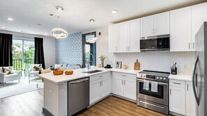 A modern kitchen with white cabinets, stainless steel appliances, and a large island with a sink. - Downtown Nashville 2BR Condo Balcony & Parking Near Broadway (Nashville)