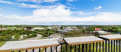 A high vantage point overlooking a cityscape with a highway, greenery, and a clear sky.