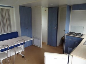 Une cuisine compacte comprenant une cuisinière, une table à manger avec des chaises et un coin cuisine.