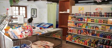 A small grocery store with shelves stocked with various food items and a checkout counter.