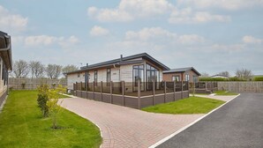 A modern single-story house with a covered patio, a paved driveway, and a well-maintained lawn. - Host Stay Puffin s Rest (Saltburn-by-the-Sea)