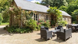 A stone building with a garden, outdoor seating, and a bicycle. - ZEcamping 5 étoiles parc aquatique tente TV LV BBQ 116m2 (Quimper)