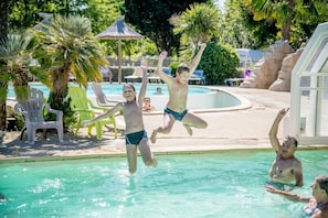 Un espace piscine avec des chaises longues et un petit bâtiment.