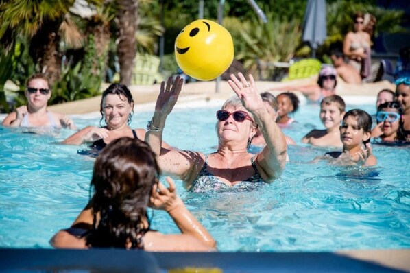 Um grupo de pessoas em uma piscina com uma bola amarela.