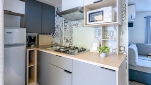 Une cuisine compacte équipée d’une cuisinière à gaz, d’un four à micro-ondes et d’une machine à café.