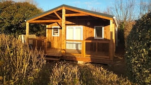 A wooden cabin with a pitched roof, a small porch, and a window.