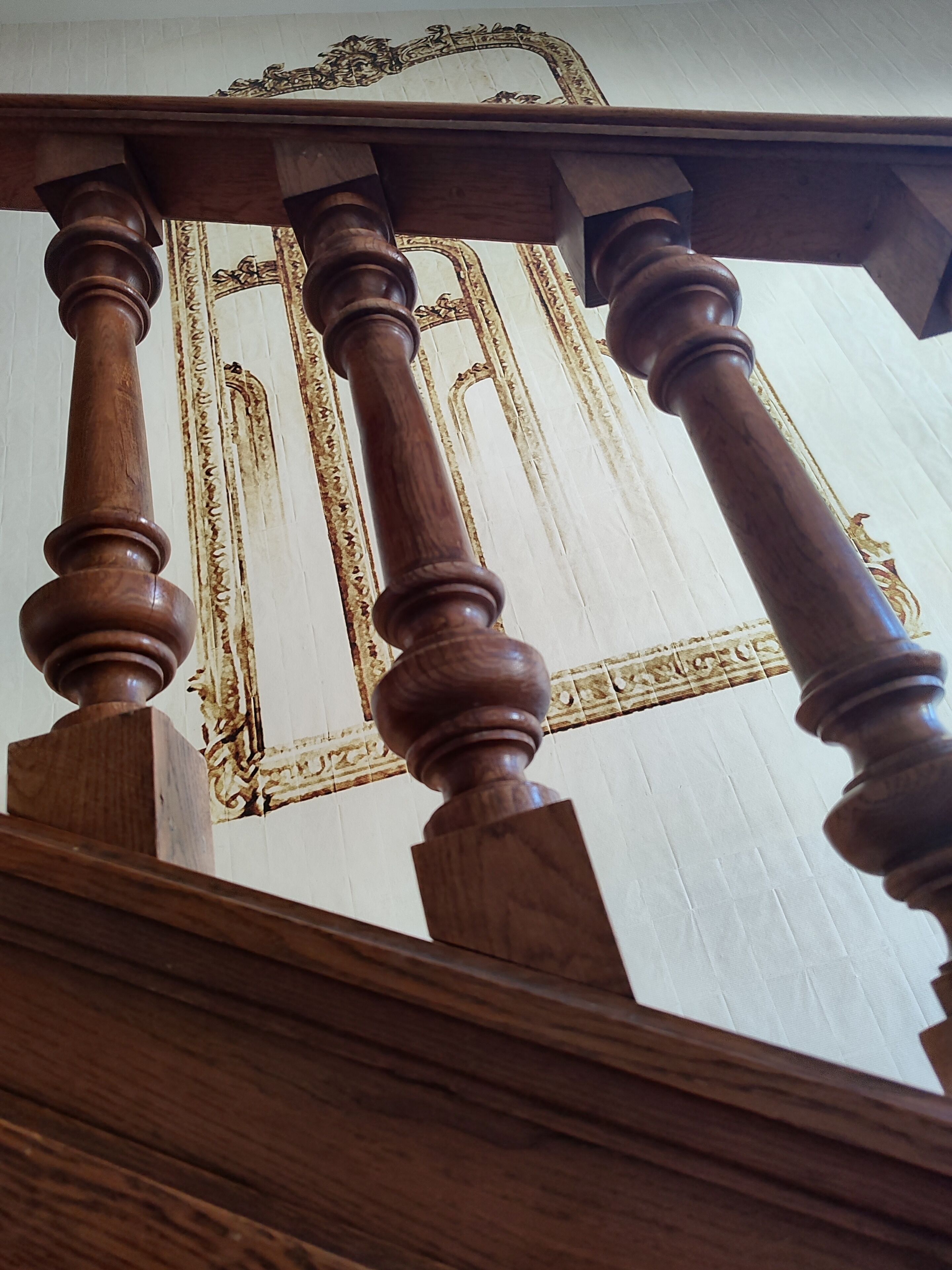 A wooden staircase with ornate balusters and a decorative ceiling.