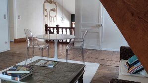 A spacious room with a wooden ceiling, a dining table with chairs, and a large mirror. - Suite de Charme en Mezzanine (Remiremont)