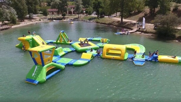 An outdoor water park with inflatable play structures and a sandy area. - ZEcamping 3 étoiles piscine animations locatif TV LV clim 33m2 4 pers (Nailloux)