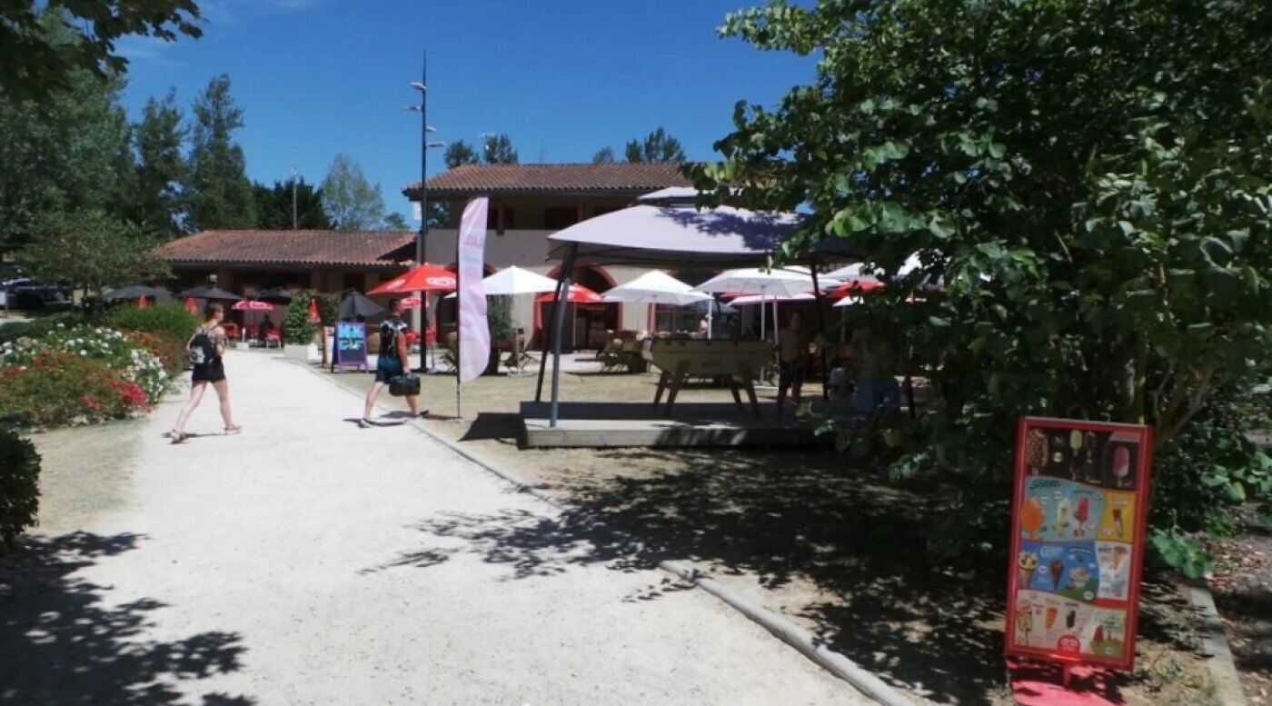 A restaurant with outdoor seating, umbrellas, and a signboard.