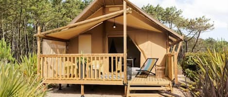 A wooden cabin with a balcony, surrounded by trees.