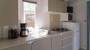 A compact kitchen with a gas stove, a microwave, and a refrigerator.
