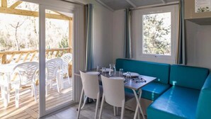 A room with a table and chairs, a teal sofa, and a window with curtains.