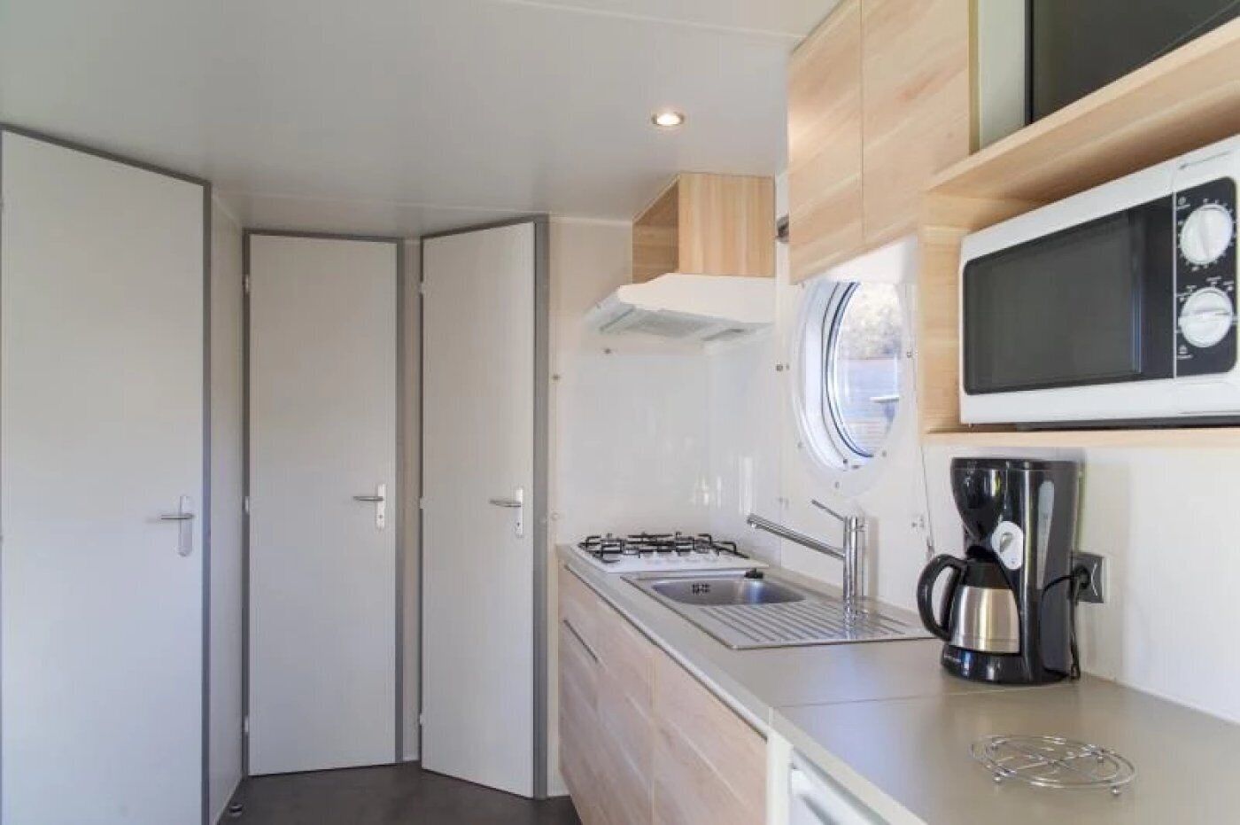 Een kleine keuken met een gasfornuis, spoelbak en een magnetron.