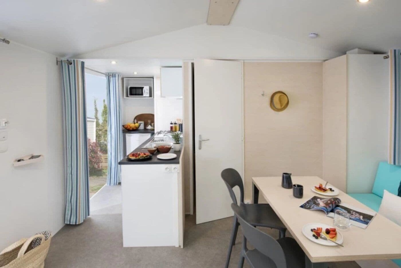 A compact living space with a kitchenette, dining area, and a view of the outdoors.