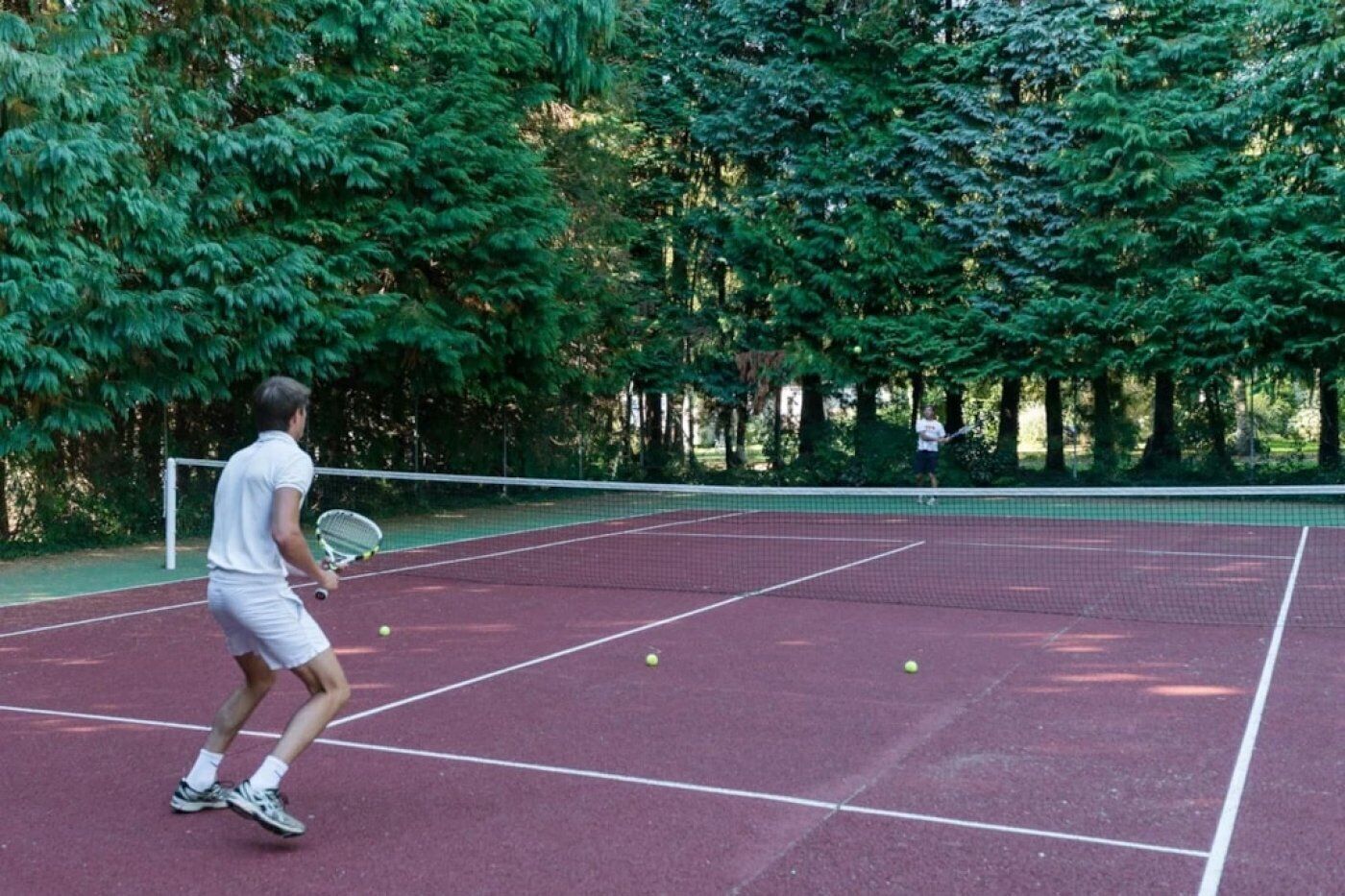 An outdoor tennis court surrounded by trees.