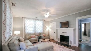 Una sala de estar con chimenea, ventilador de techo y televisión.