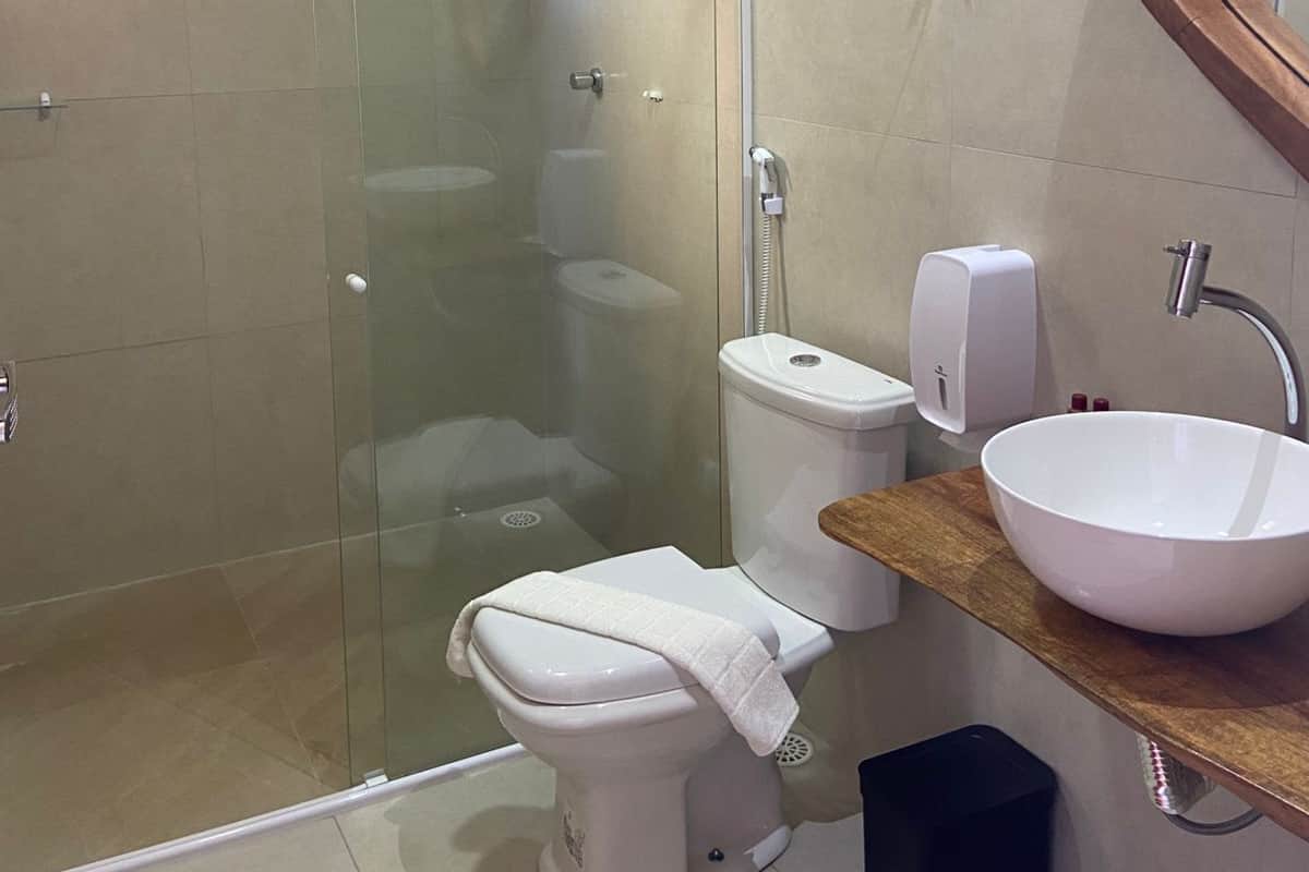 Ein modernes Badezimmer mit einer Duschkabine aus Glas, einer weißen Toilette, einem Waschbecken mit Holzablage und einem Spiegel mit Holzrahmen.