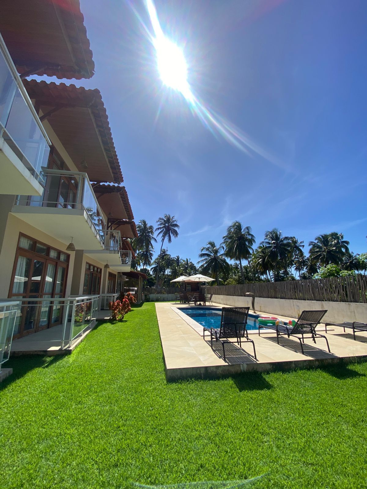 A two-story building with a swimming pool, outdoor seating, and a well-maintained lawn.