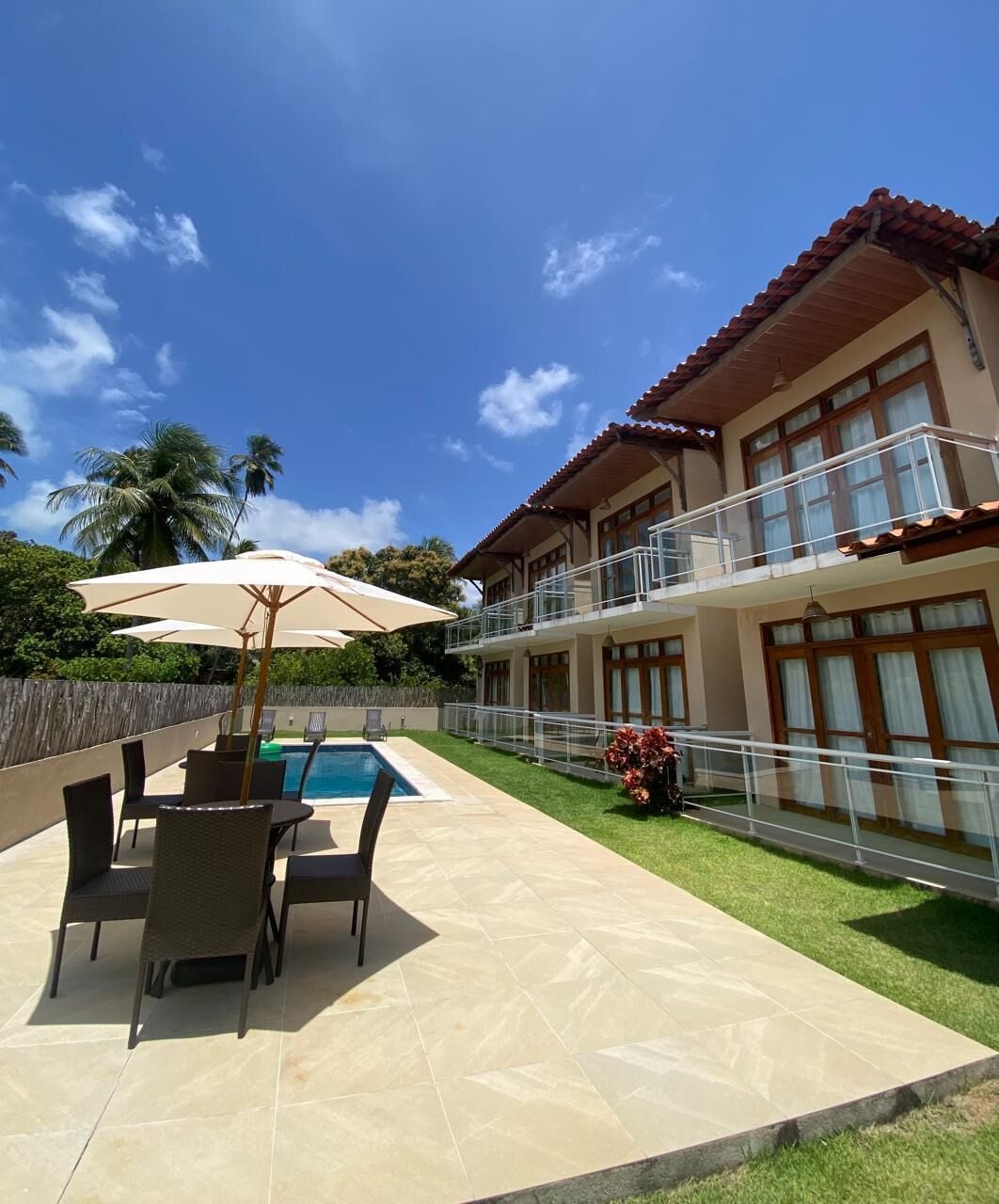 A two-story building with a swimming pool, outdoor seating, and a well-maintained lawn.