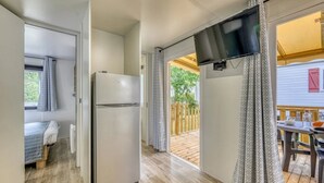Eine kompakte Küche mit Kühlschrank, ein Essbereich mit Tisch und Stühlen sowie ein Balkon mit Blick ins Freie.