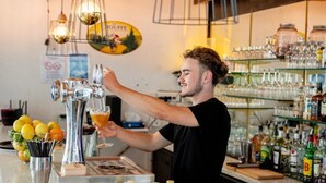 Ein Barkeeper zapft ein Getränk in ein Glas.