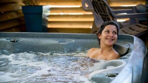 Ein Whirlpool mit einer Person darin, umgeben von Holzliegen.