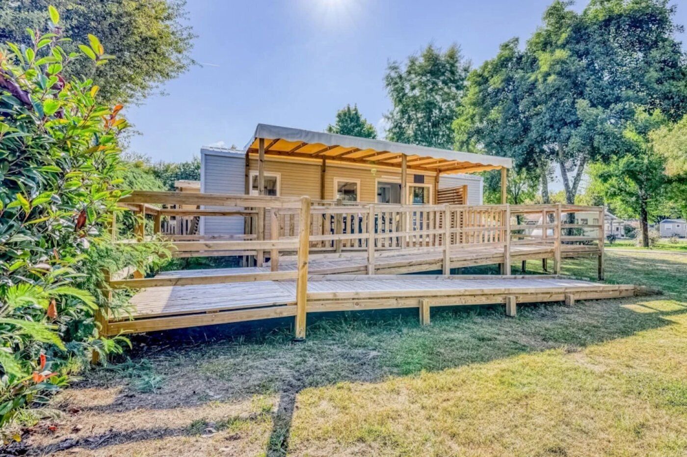 A wooden deck leading to a modern house with a covered porch and a small outdoor kitchen area.