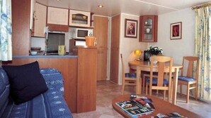 Een compacte leefruimte met een kitchenette, een eethoek en een zithoek.