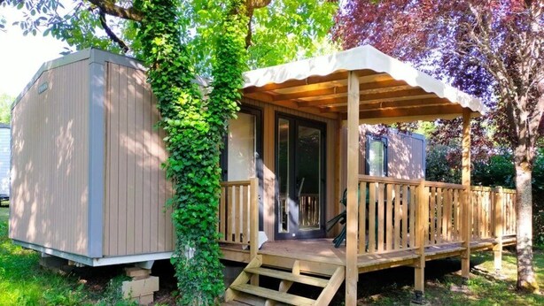 Een houten terras met een overdekte veranda, een tuinhuisje en een trap die naar de veranda leidt.