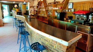 Een bar met een metselwerk aanrecht, blauwe krukken en planken met glazen en flessen.