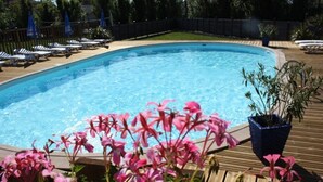 A swimming pool with lounge chairs and potted plants.