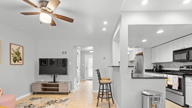 A modern kitchen with white cabinets, a black countertop, and stainless steel appliances.
